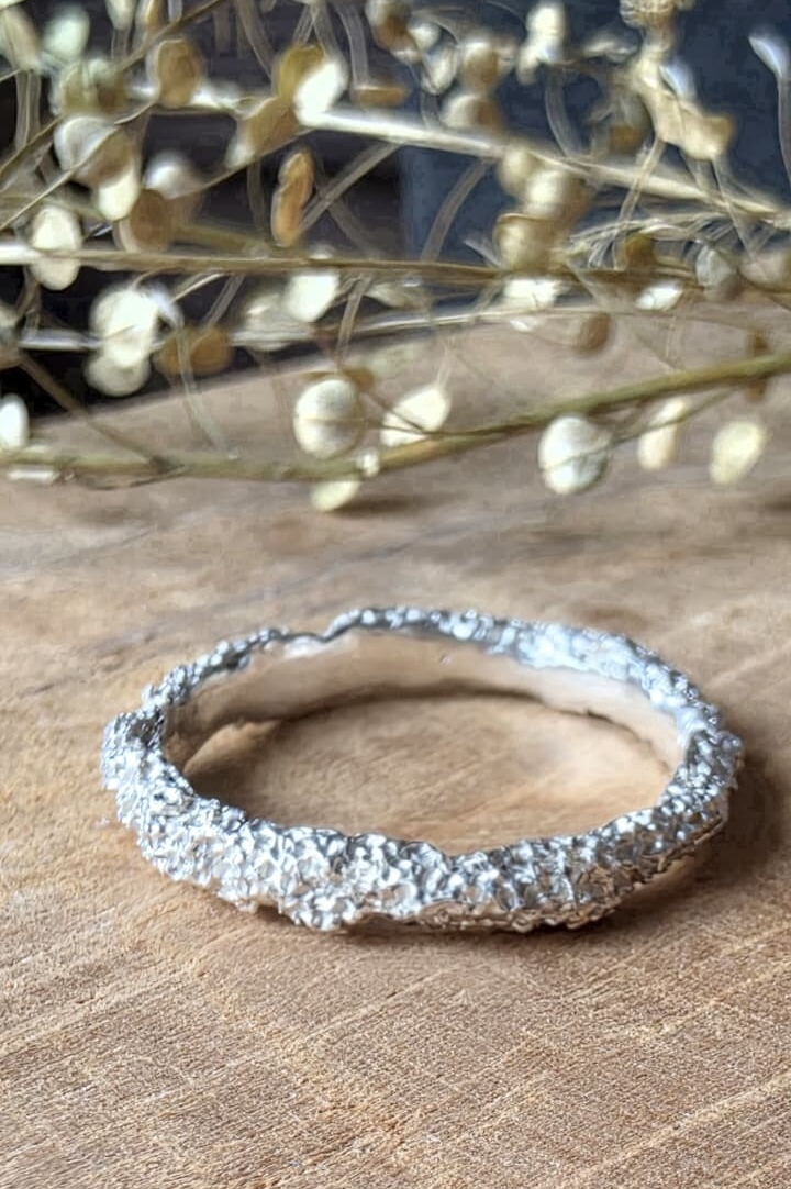 Anello artigianale in argento 925 con texture materica ispirata alla roccia grezza.