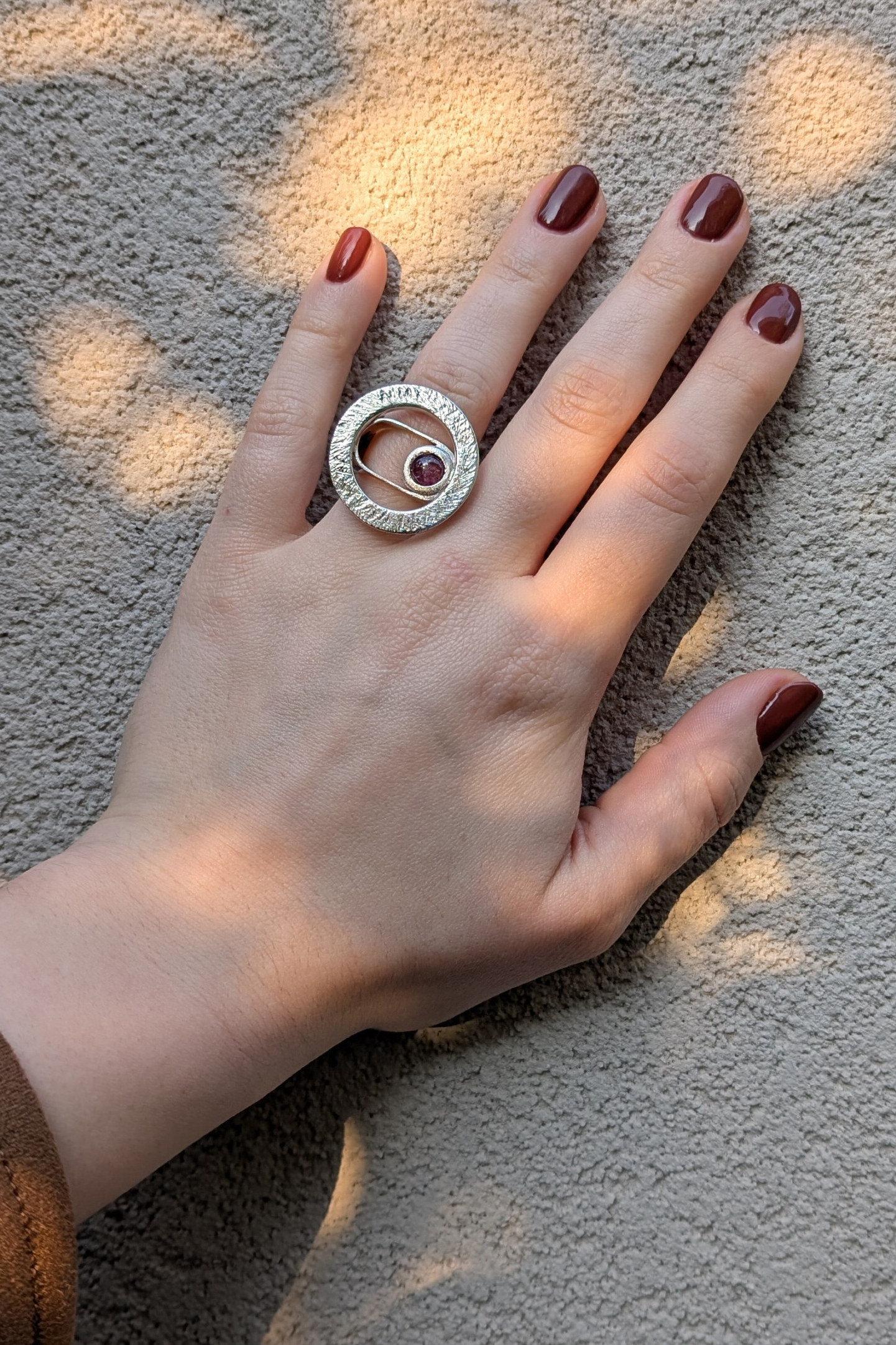 Mano che indossa l'anello Seventy in argento 925 e pietra naturale, esempio di vestibilità gioiello artigianale materico.