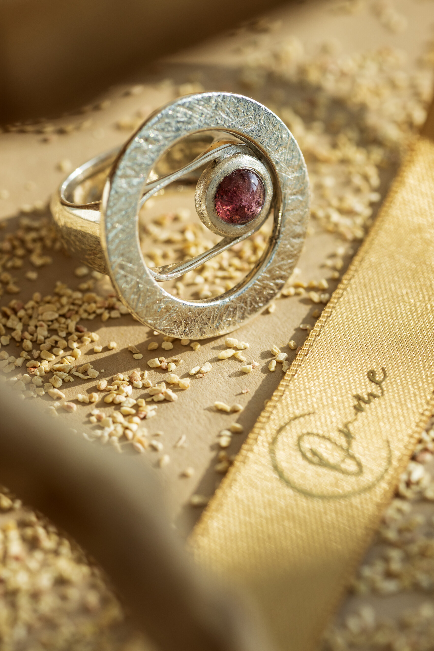 Dettaglio macro dell'incastonatura a mano su anello materico Seventy, gioiello artigianale in argento e pietra naturale.