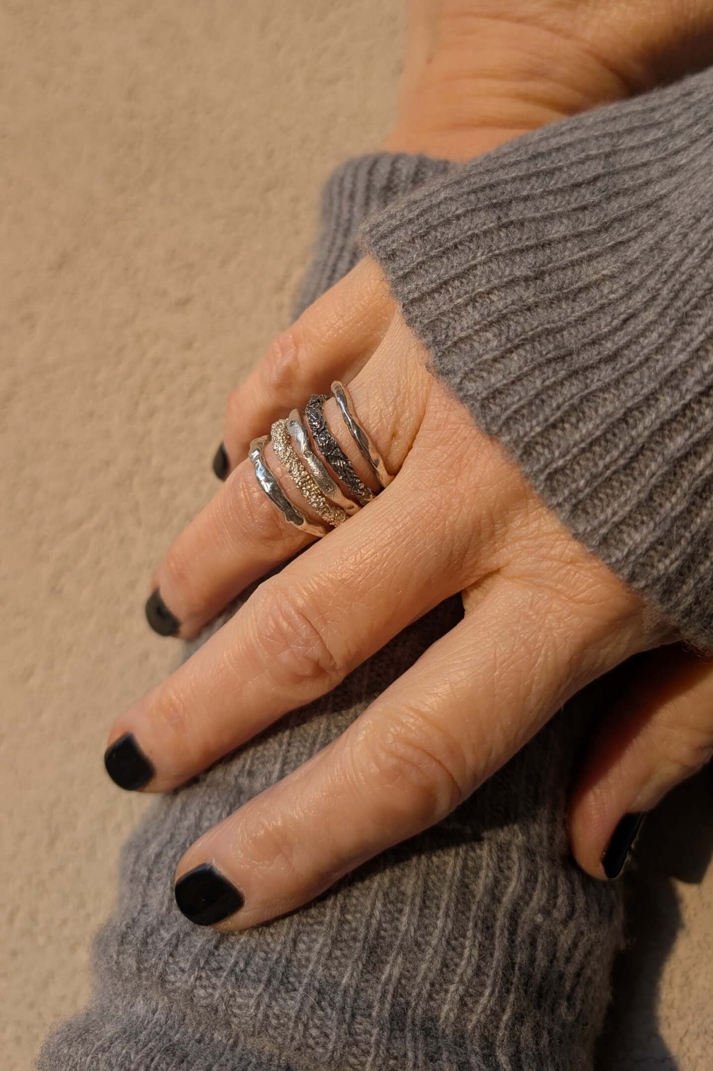 Mano con stack di anelli Caleidos: il Frammento d'Origine abbinato ai modelli bruniti