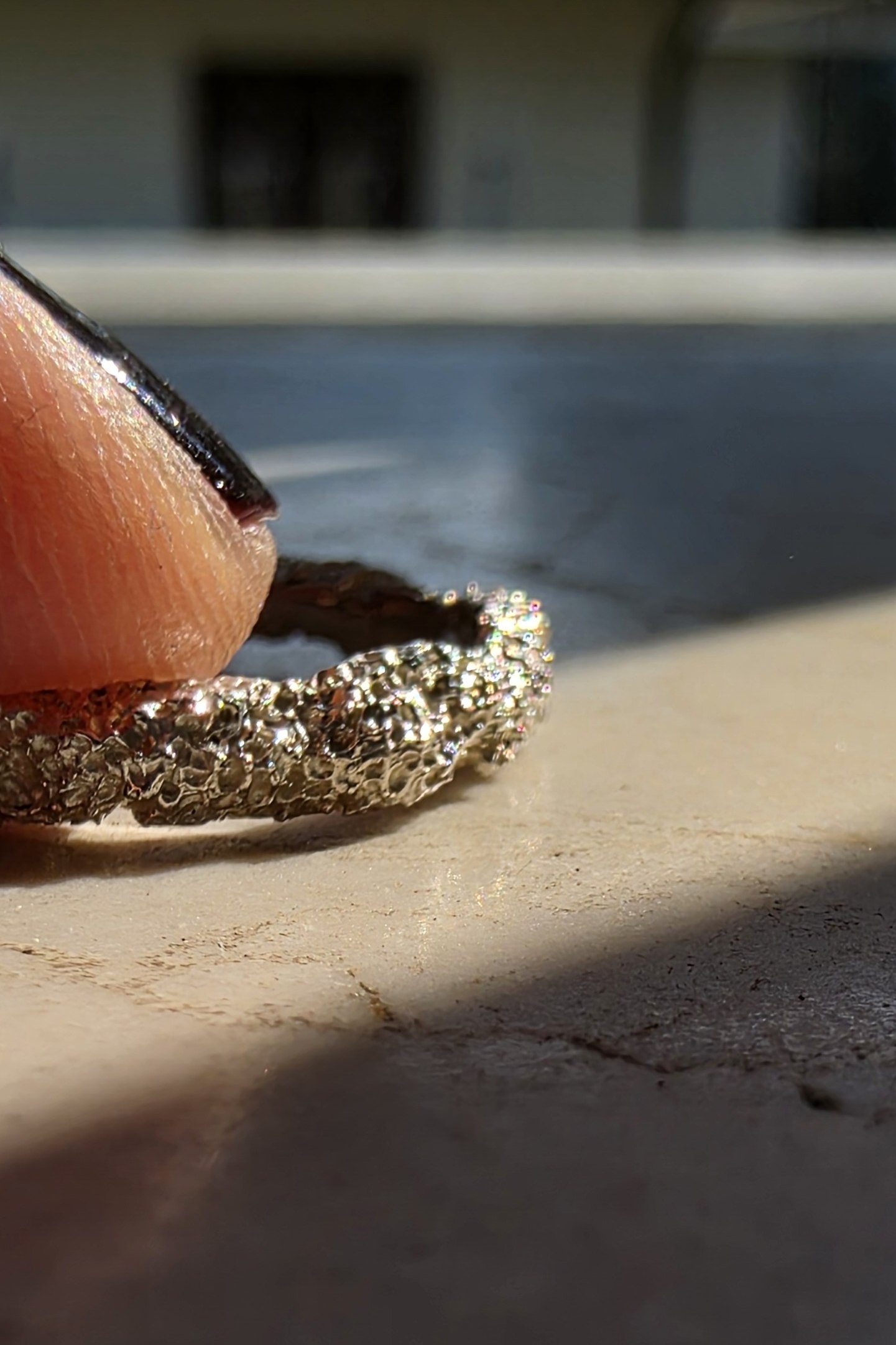 Dettaglio ravvicinato della lavorazione artigianale scultorea su argento lucido.
