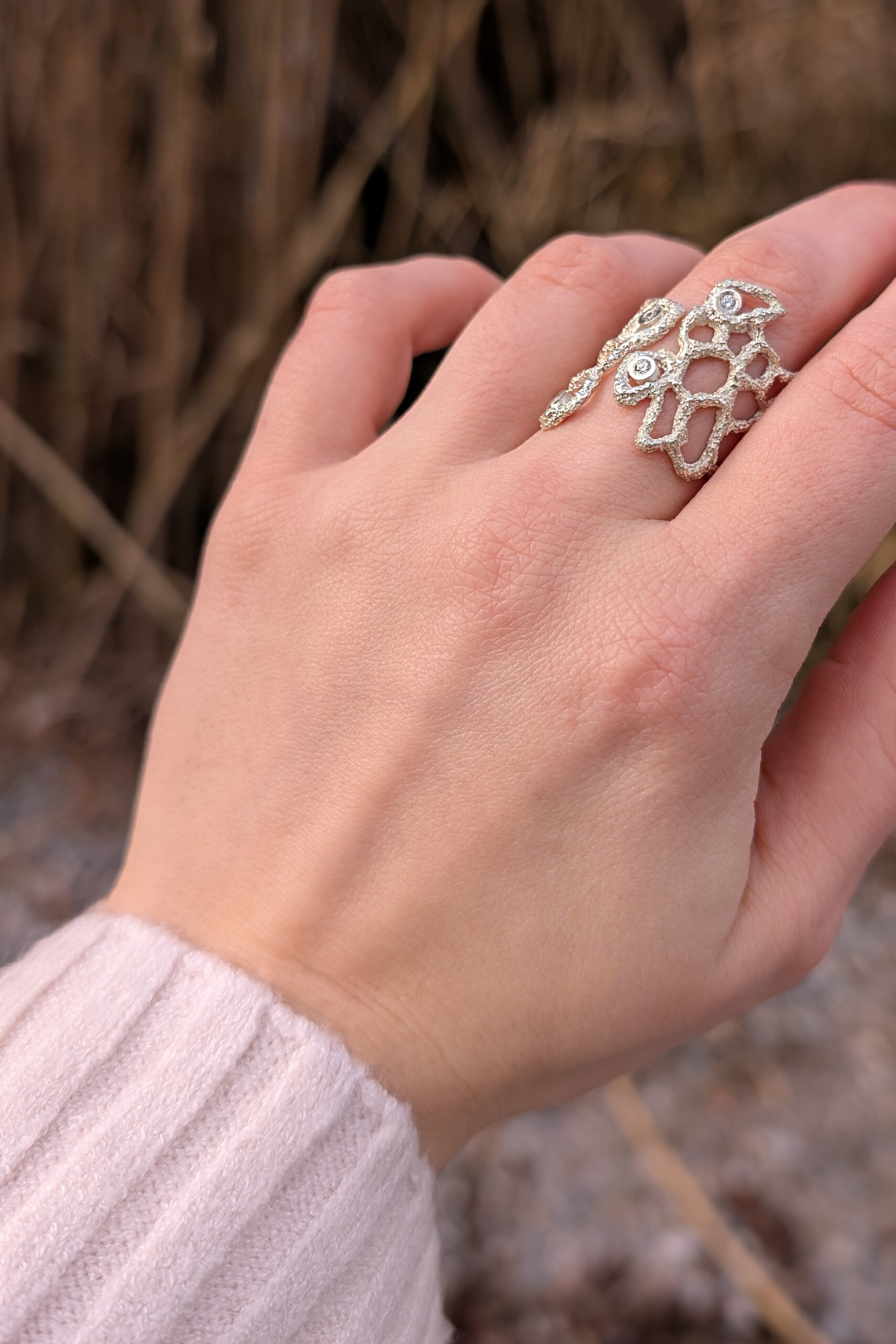 Foto lifestyle dell'anello Nebula indossato, che mette in risalto l'apertura frontale e la luminosità degli zirconi su sfondo naturale sfocato.