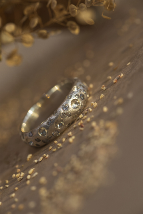 Dettaglio macro dell'anello Cratere in argento 925 con piccoli zirconi luminosi incastonati nella texture materica.