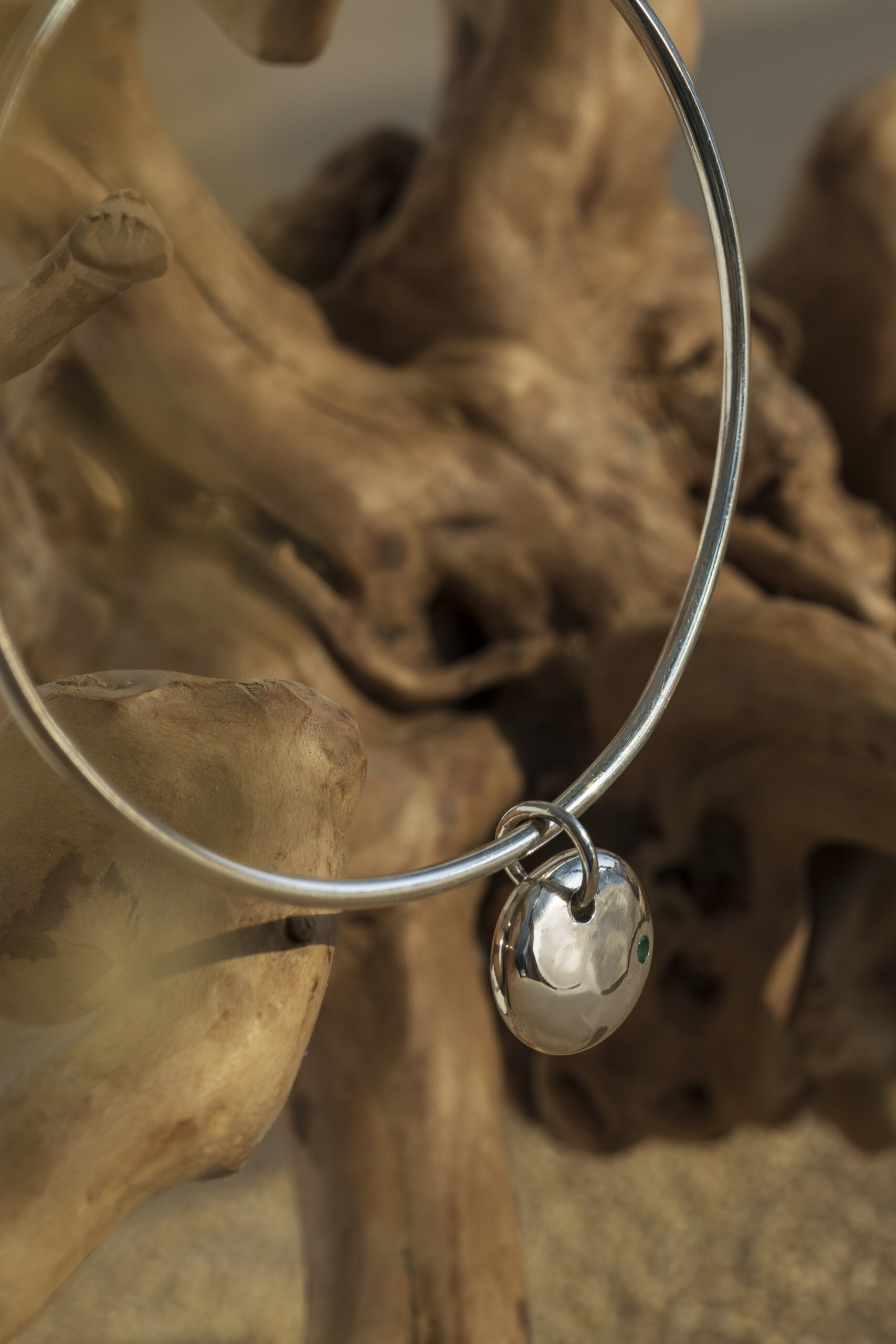 Macro che mostra la texture martellata fatta a mano sul pendente del bracciale rigido in argento 925, evidenziando l'artigianalità del pezzo unico.