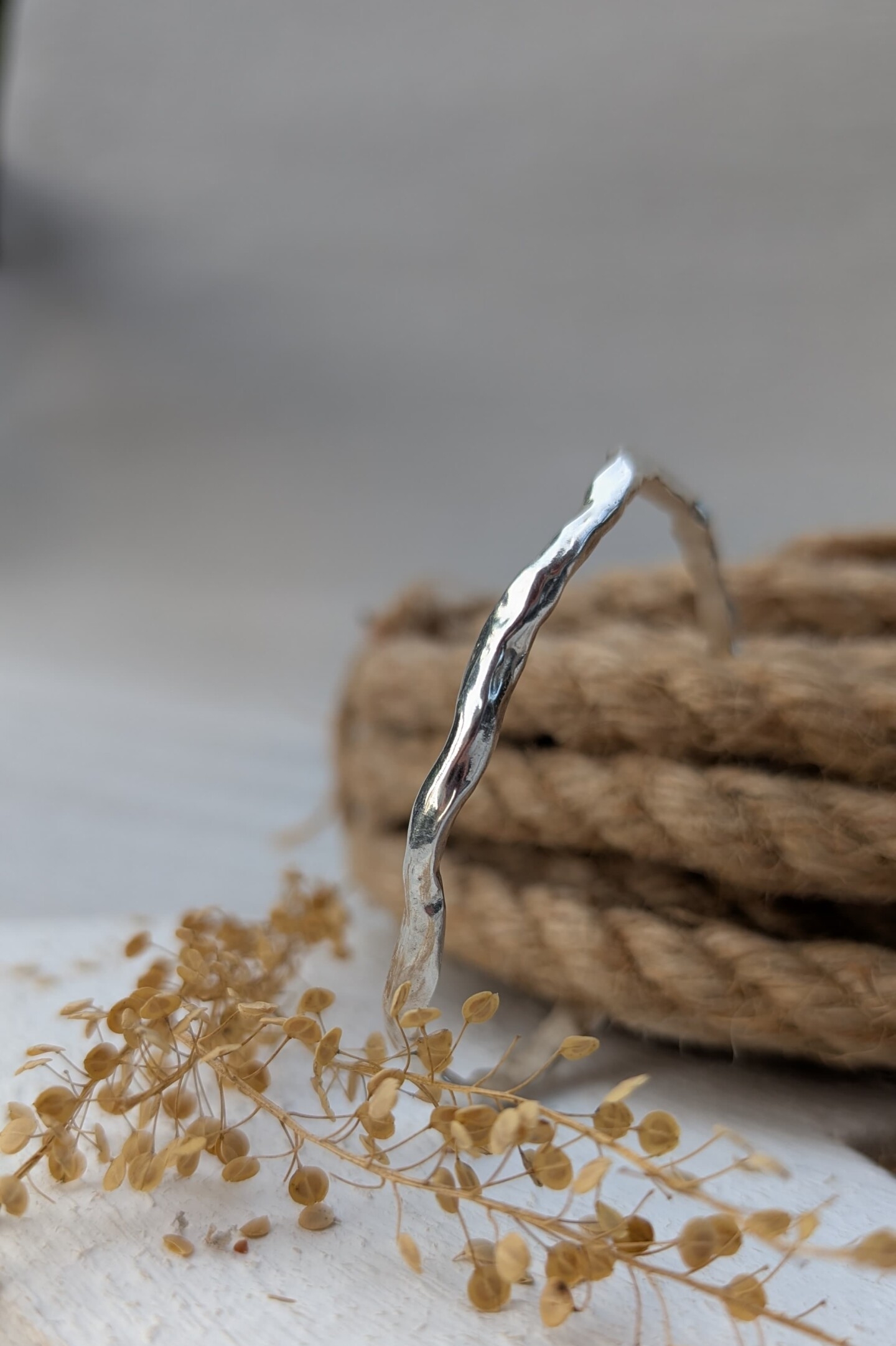 Dettaglio del bracciale rigido Lava in argento lucido, caratterizzato dai giochi di luce creati dalla superficie mossa e artigianale.