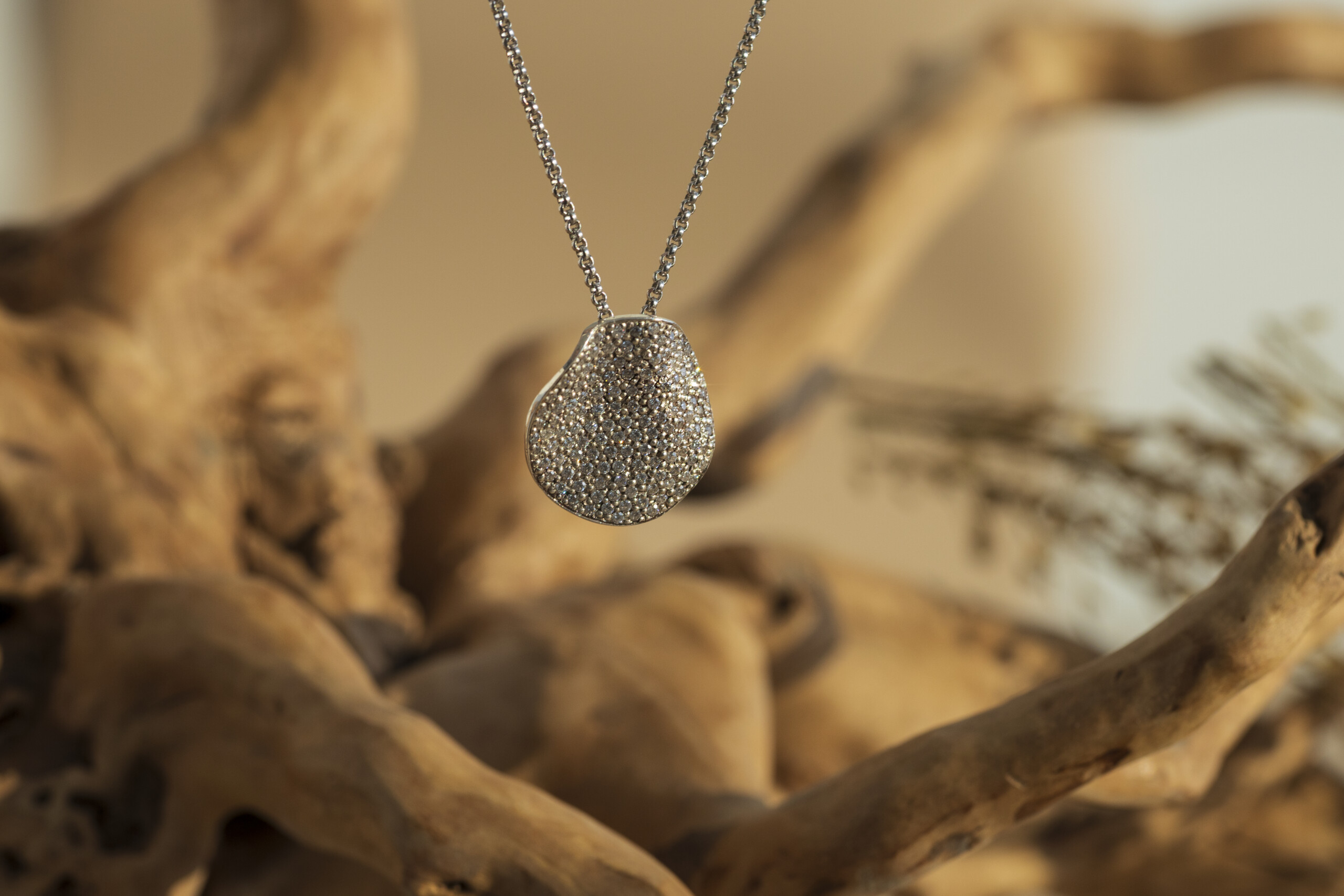 copertina-collezione-moon-ciondolo-pave-argento-artigianale.jpg Pendente irregolare con piccolo pavé di zirconi luminosi della collezione Moon, inserito in una catena in argento su sfondo naturale caldo