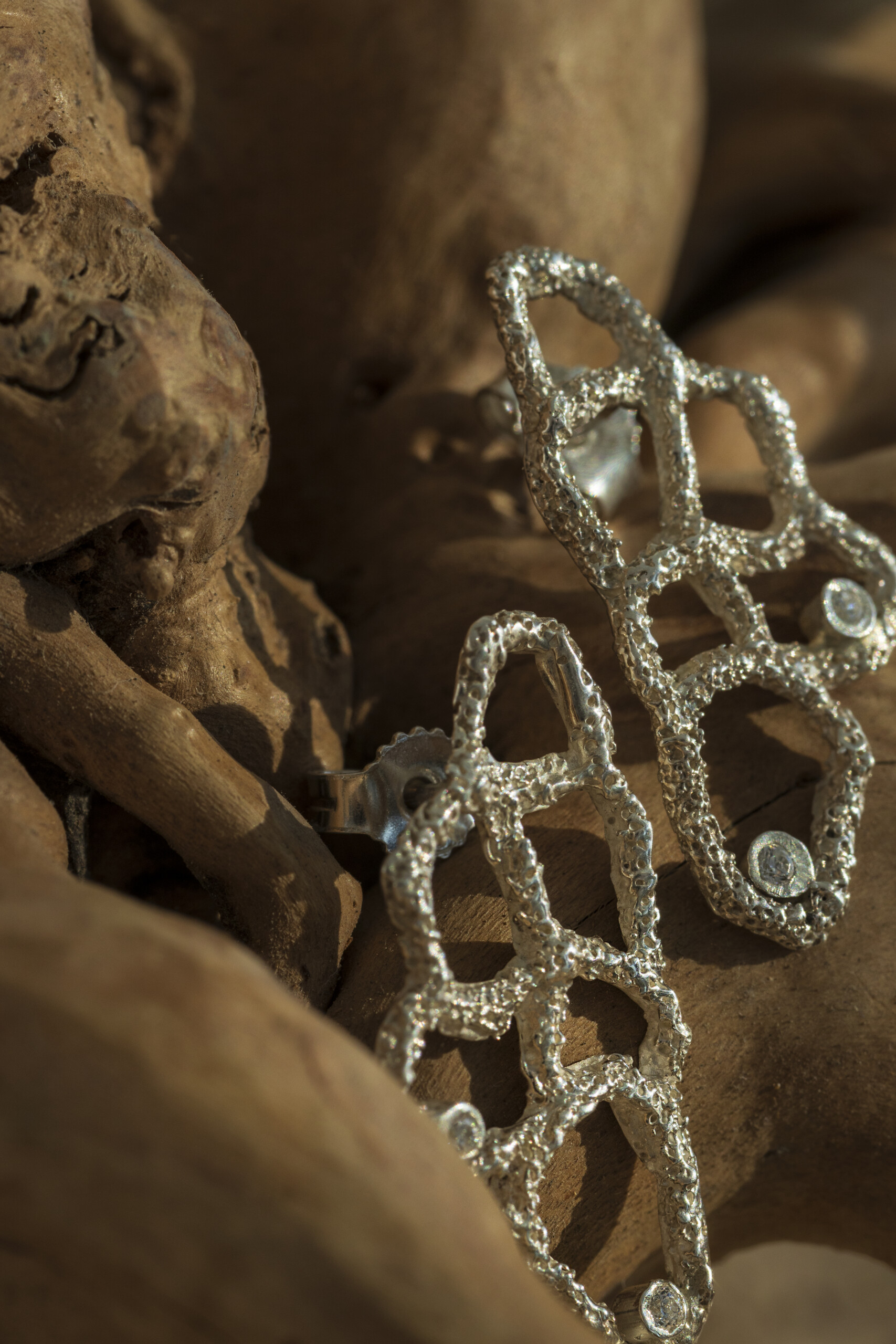 Macro ravvicinata degli orecchini Nebula che mostra la finitura irregolare dell'argento e la qualità dell'incastonatura degli zirconi realizzata nel nostro laboratorio orafo.