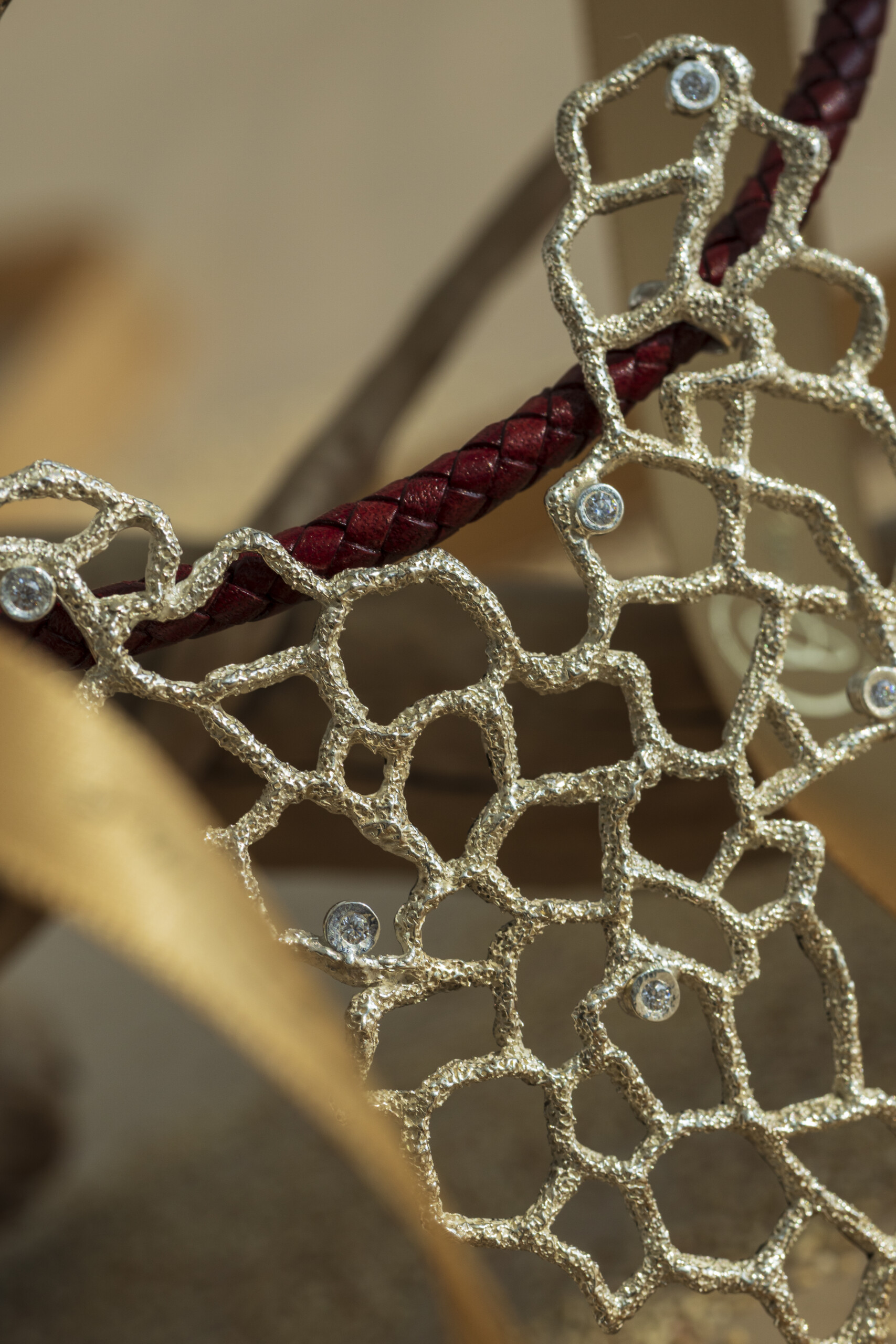 Primo piano macro sulla rete organica del ciondolo Nebula che mostra gli zirconi incastonati a mano e la superficie irregolare e materica della fusione a cera persa.