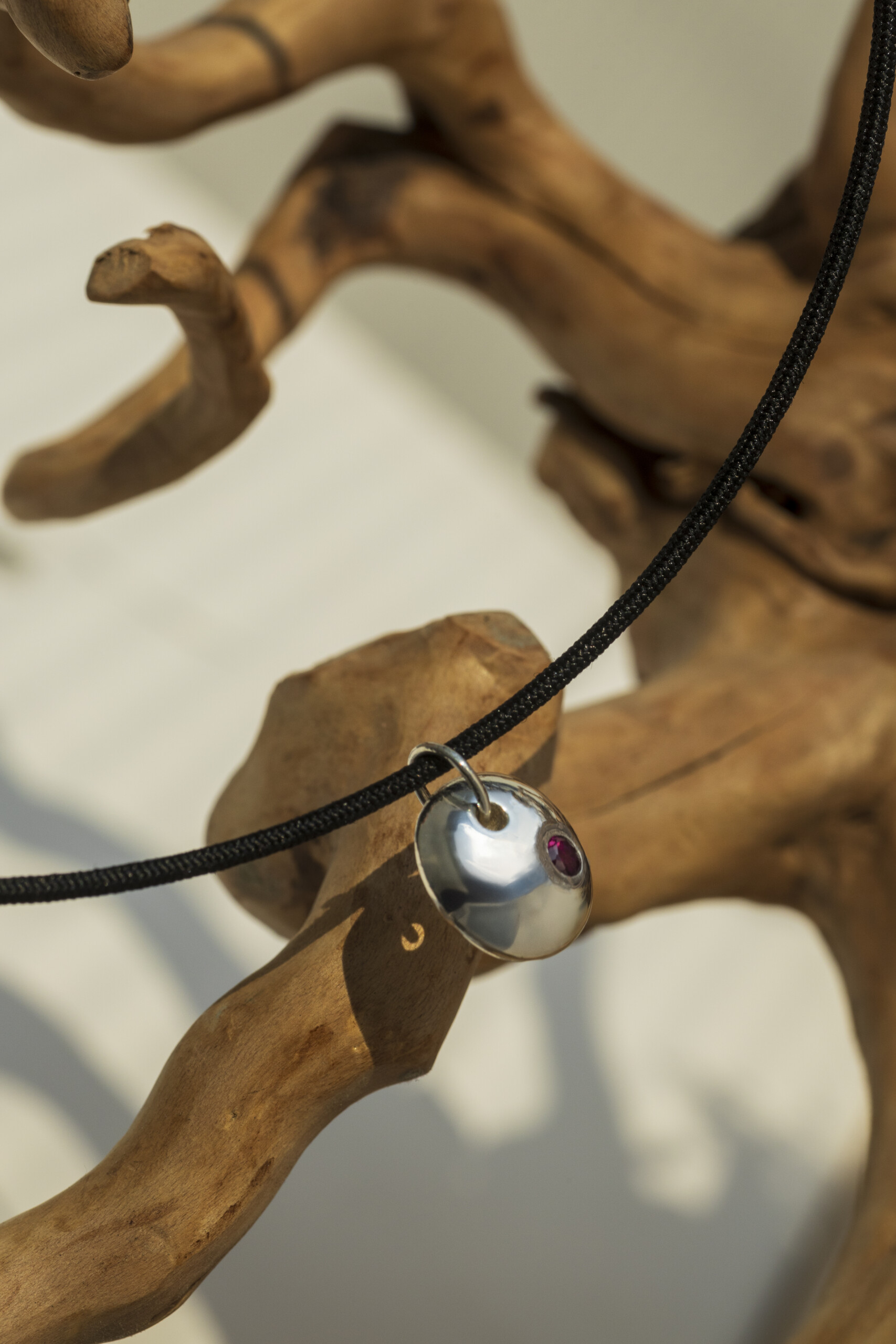 Vista angolata del ciondolo Pepita con rubino rosso, esempio di gioielleria artigianale che unisce design naturalistico e tecnica della cera persa.