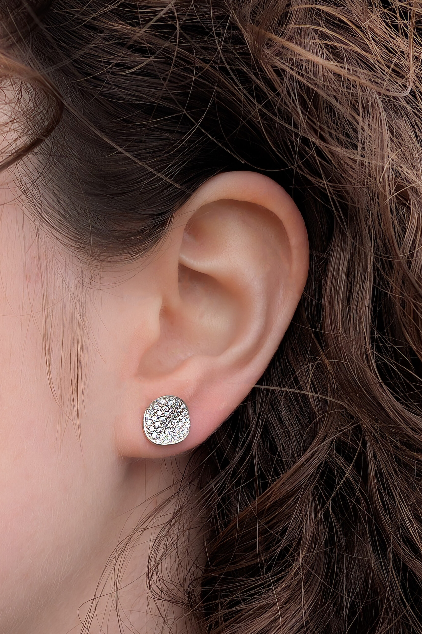 Dettaglio di un orecchino Moon a lobo indossato; la luce cattura il pavé di zirconi creando un punto luce elegante e contemporaneo.