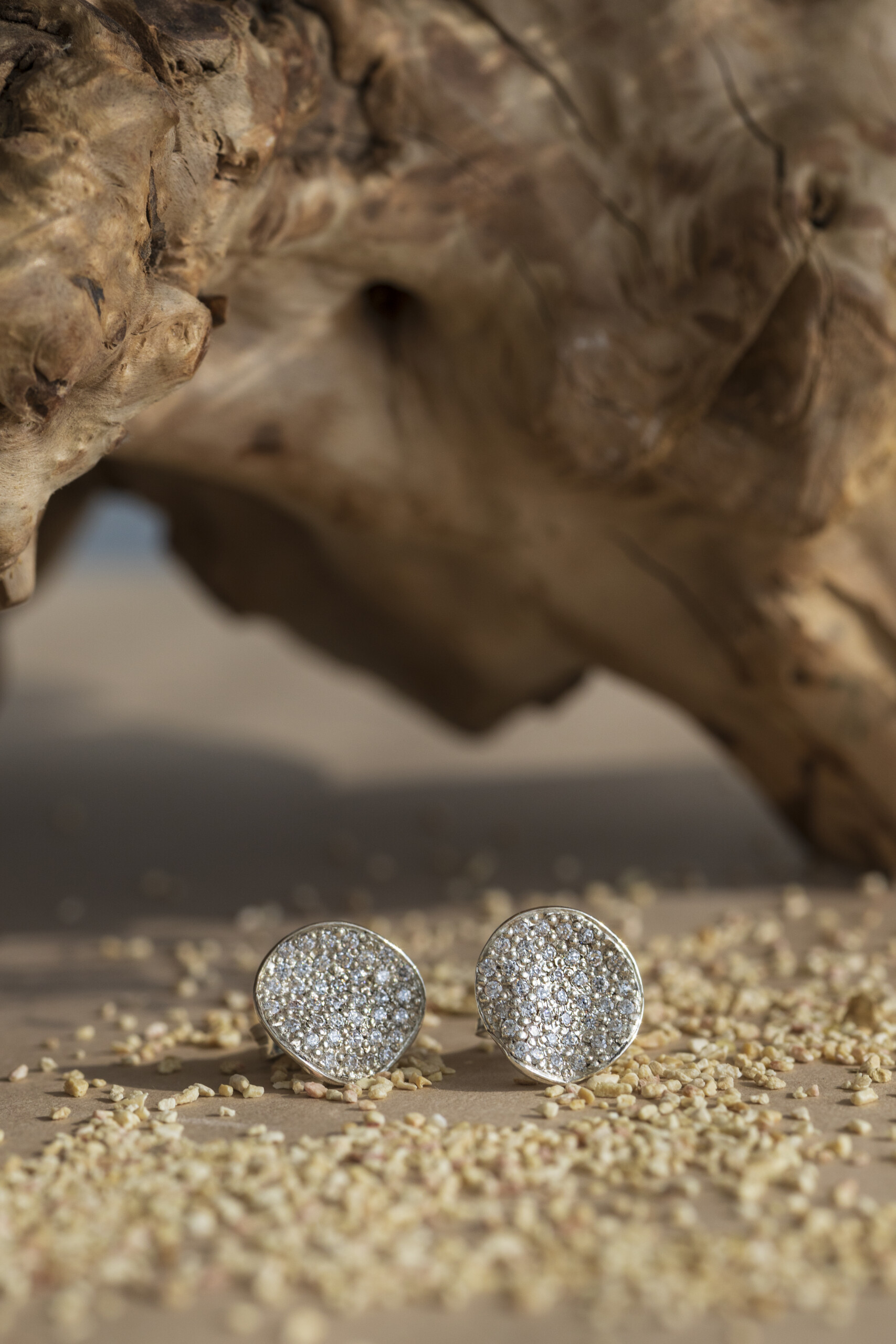 Coppia di orecchini a lobo della collezione Moon in argento 925 con pavé di zirconi, presentati su un fondo sabbioso naturale.